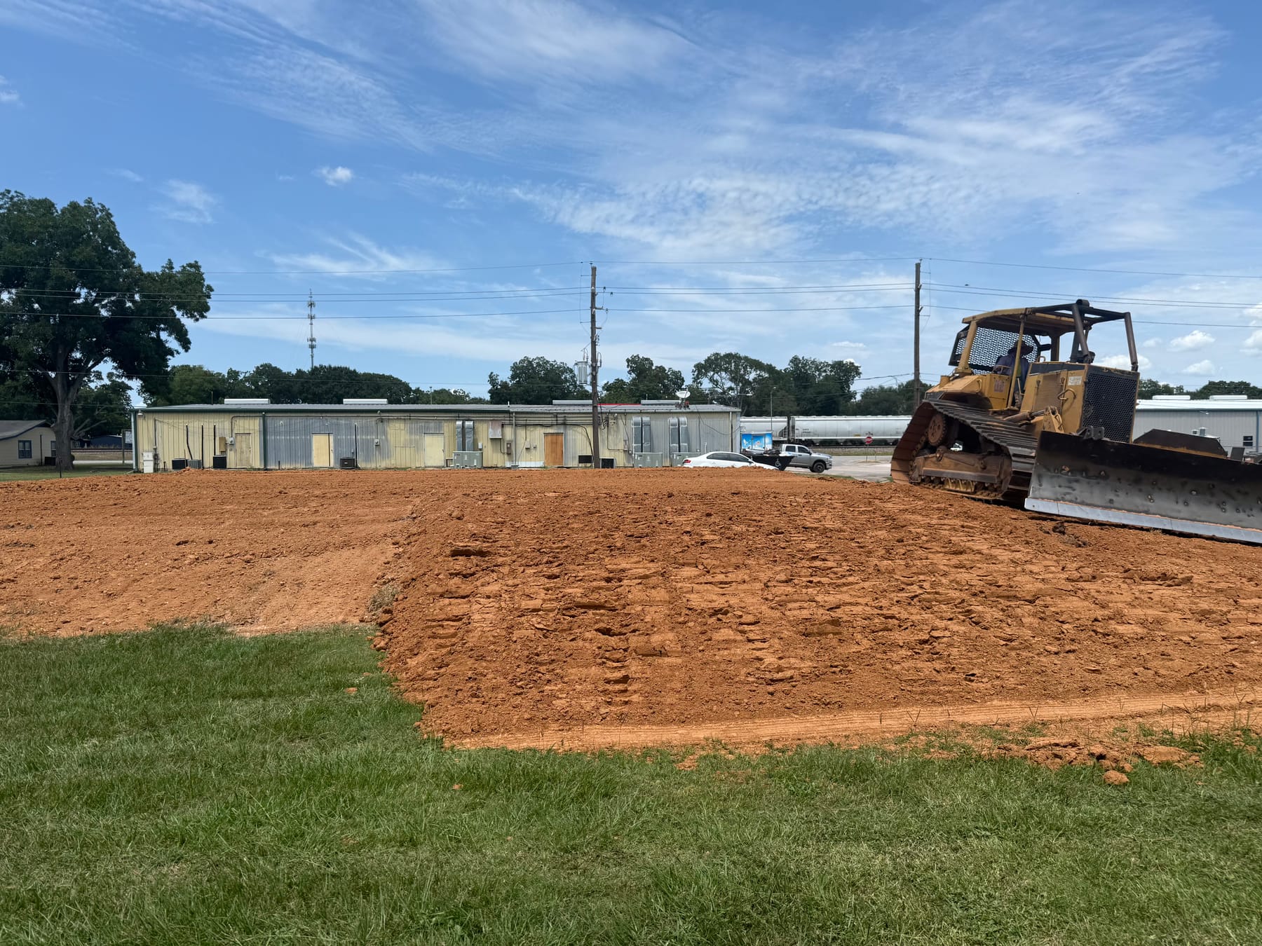 A bulldozer pushing and leveling dirt on a cleared lot.